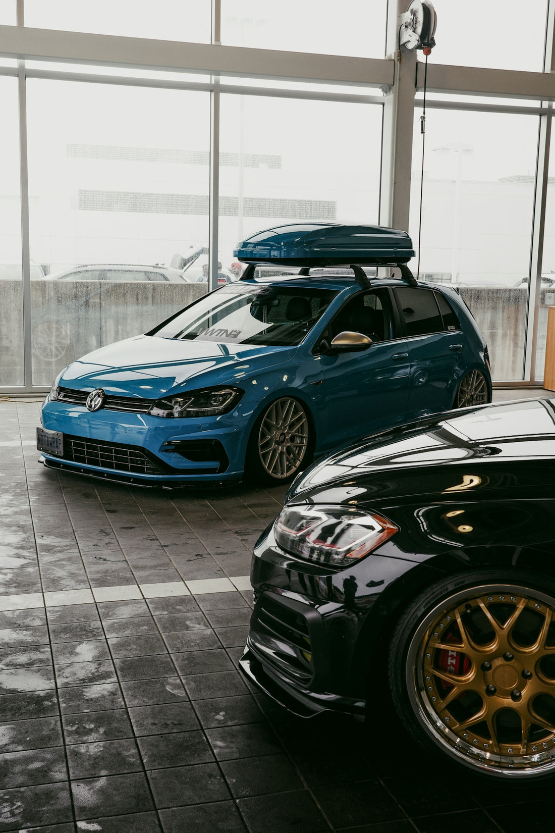 Modified blue volkswagen golf with roof box and black car